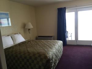 um quarto de hotel com uma cama e uma porta de vidro deslizante em Fairview Beachfront Inn em Mackinaw City