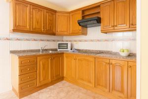 a kitchen with wooden cabinets and a microwave at Be six Playa La Arena in Puerto de Santiago