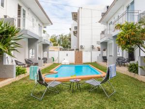 a pool in the backyard of a house with chairs and a table at Amis Apartments Mauritius in Cap Malheureux