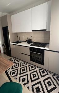 a kitchen with white cabinets and a black and white rug at Mareea Luxury Apartment-Energia Residence in Constanţa