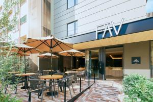 an outdoor patio with tables and chairs and umbrellas at FAV LUX Nagasaki in Nagasaki