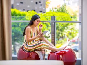 Una mujer con un vestido de rayas sentada en un paseo en autobús en ibis Styles Singapore Albert, en Singapur