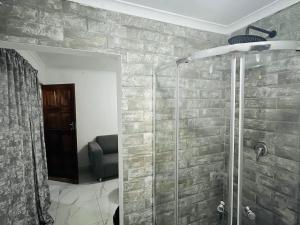 a bathroom with a glass shower with a chair at Mohwelere Guest House in Pretoria