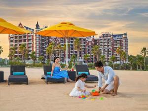 a man and woman playing with a child on the beach at Mövenpick Resort Phan Thiet in Phan Thiet