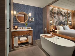 a bathroom with a bed and a bathtub and a bedroom at Mövenpick Resort Phan Thiet in Phan Thiet