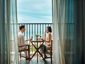 a man and woman sitting at a table on a balcony at Mövenpick Resort Phan Thiet in Phan Thiet