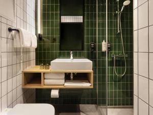 a green tiled bathroom with a sink and a shower at ibis Styles Copenhagen Orestad in Copenhagen +51 photos