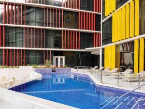 un immeuble avec une piscine devant un immeuble dans l'établissement ibis Doha, à Doha