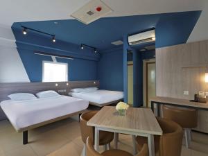 a room with two beds and a table in it at ibis budget Phnom Penh Riverside in Phnom Penh