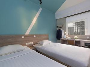two beds in a hotel room with a window at ibis budget Phnom Penh Riverside in Phnom Penh