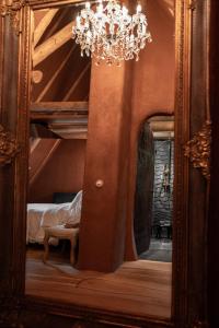 a mirror in a bedroom with a chandelier at Castelul de Lut - Eco Boutique Guesthouse in Porumbacu de Sus