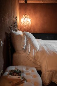 a bedroom with a white bed with a chandelier at Castelul de Lut - Eco Boutique Guesthouse in Porumbacu de Sus