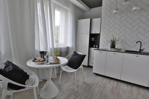 a white kitchen with a white table and chairs at Apartament Zbożowy Rynek 2 in Bydgoszcz