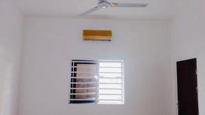 eine weiße Wand mit einem Fenster und einem Deckenventilator in der Unterkunft Cozy studio I with AC and fan in Akassato