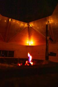 a wooden building with a fire in front of it at night at Arctic Aurora Villa With A Hut - Northern Lights and Adventures in the Hometown of Santa Claus, Rovaniemi in Rovaniemi