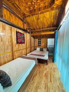 une chambre avec deux lits et un plafond en bois dans l'établissement Happy Heart Homestay - Nhà số 07 bản Lác, à Mai Châu