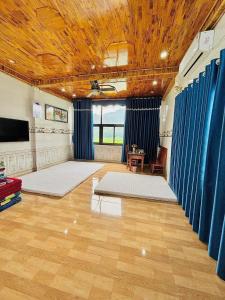 une grande pièce avec des rideaux bleus et des tapis blancs dans l'établissement Happy Heart Homestay - Nhà số 07 bản Lác, à Mai Châu
