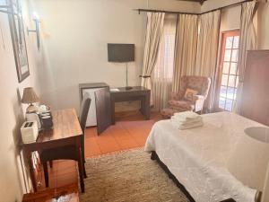 une chambre avec un lit, un bureau et une chaise dans l'établissement Khaya Africa Guesthouse, à Midrand
