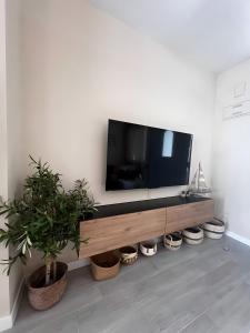 ein Wohnzimmer mit einem Fernseher an einer Wand mit Pflanzen in der Unterkunft Adosado La Dolce Vita in Molinell