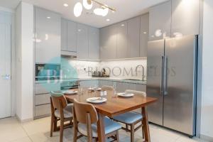 una cucina con tavolo e sedie in legno e frigorifero di Bloomfields Sea View 2br Apartment a Fujaira