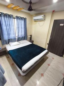 a bed in a room with blue curtains and a door at Hotel shivalay in Dwarka +7 photos