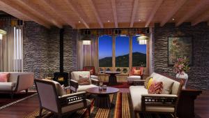 un salon avec des chaises et des tables et un mur en pierre dans l'établissement Taj Gangtey Resort and Spa Bhutan, à Tshalunang