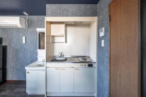 a kitchen with white cabinets and a sink at Silk Court 201 in Chitose