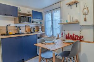 a kitchen with blue cabinets and a wooden table with chairs at L'Appart'Mans -charmant-studio-centre ville-2 pers in Le Mans