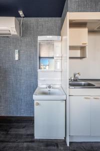 a kitchen with white cabinets and a sink at Silk Court 201 in Chitose