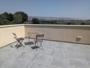 a patio with two chairs and a table on a roof at River and Mountains in HaGoshrim +16 photos