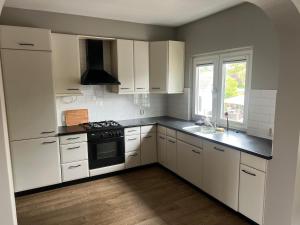 Una cocina con gabinetes blancos y un horno de estufa. en Provence Driehuis Apartment, en Driehuis 10 fotos más