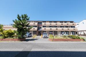 een groot gebouw met auto's geparkeerd op een parkeerplaats bij TDR9分 駄菓子とアートの可愛いミュージアム宿 夢が詰まった小さな宝箱 -TAMU-LAND Urayasu- in Urayasu