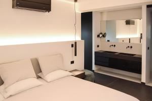 a bedroom with a white bed and a mirror at White & Black Aegina - Private Garden & Parking in Áyioi Asómatoi