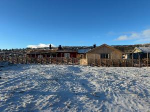 a snow covered yard with a fence and houses at Bottheimsætra 