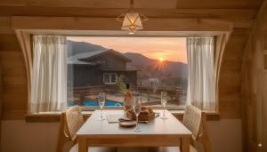 Un comedor con una mesa y una ventana con la puesta de sol. en Gapyeong Manwol Aegyeon Pool Glamping, en Gapyeong