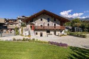 a large stone house with a balcony and a yard at Le Grenier d'Antan - Relax Suite in Aosta