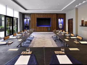 una sala de conferencias con mesas largas y una pantalla grande en Movenpick Hotel Abidjan-Accor Group, en Abiyán