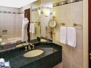 a bathroom with a sink and a mirror at Mövenpick Grand Al Bustan in Dubai