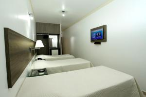 a hotel room with two beds and a tv at Hotel Match Point in São Carlos