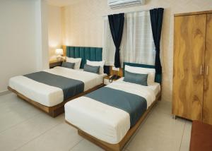 two beds in a hotel room withskirts at Hotel Maya Elite in Bhopal