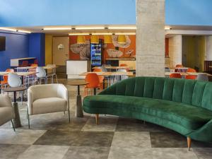 ガラニュンスにあるIbis Styles Garanhunsのテーブルと椅子付きの客室内の緑のソファ