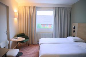 Cette chambre comprend deux lits, une table et une fenêtre. dans l'établissement Hôtel Restaurant L'Ours De Mutzig, à Mutzig