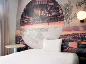 a bedroom with a bed and a poster of a city at ibis styles Paris Montmartre Batignolles in Paris +41 photos
