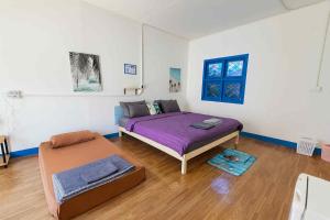 ein Schlafzimmer mit einem lila Bett und einem Ottomanen in der Unterkunft Baan AoKao KohMak in Ko Mak + 120 Fotos