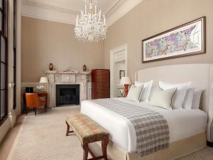 a bedroom with a large white bed and a fireplace at Raffles London at The OWO in London