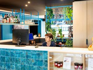 a woman sitting at a counter in a bar at Ibis Styles Miramas in Miramas