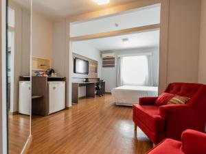 a living room with a red couch and a bed at Ibis Styles Campinas Alphaville in Campinas