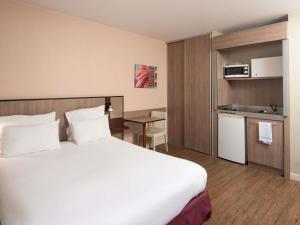 a hotel room with a large bed and a kitchen at Adagio Access Lyon Centre Université in Lyon