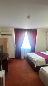 a hotel room with two beds and a window at Hotel Poem in Călăraşi