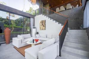 a living room with white furniture and a staircase at The Garden Villas in Ubud